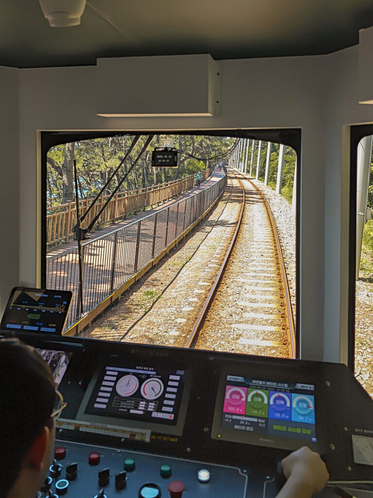 Пляжный поезд Blue Line Park едет вдоль моря в Пусане